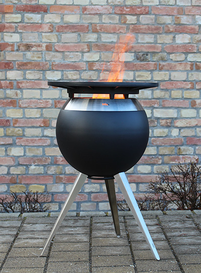 A fire pit sitting in front of a brick wall the Moon 45 complements the moment with its thoughtful design.