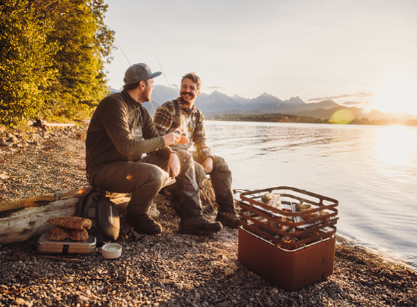 Der perfekte Fang Ein Mann und eine Frau sitzen an einem Strand neben einem See.
