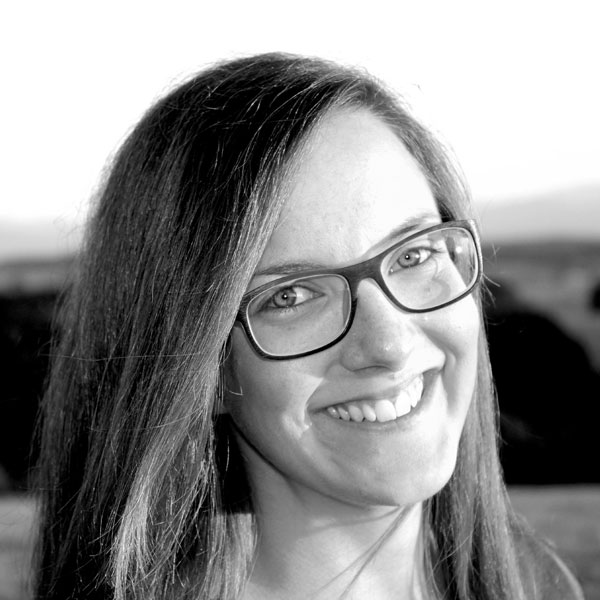 Une femme avec des lunettes sourit à l'appareil photo.