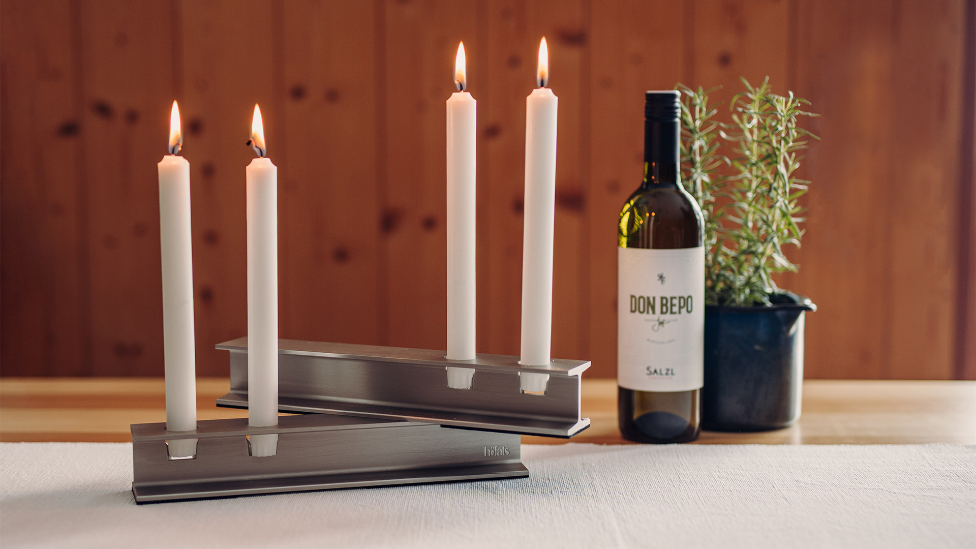 A depiction of a bottle of wine and a candle holder, featuring the 00801 Henry Metal II silver as a central and purposeful element.