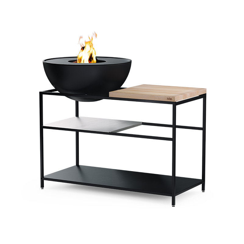 FIRE KITCHEN avec BOWL 70 Set Plancha Grille basse Illustré est un bol à feu noir sur un support, avec le FIRE KITCHEN avec le BOWL 70 Plancha BBQ Set incl. roues.