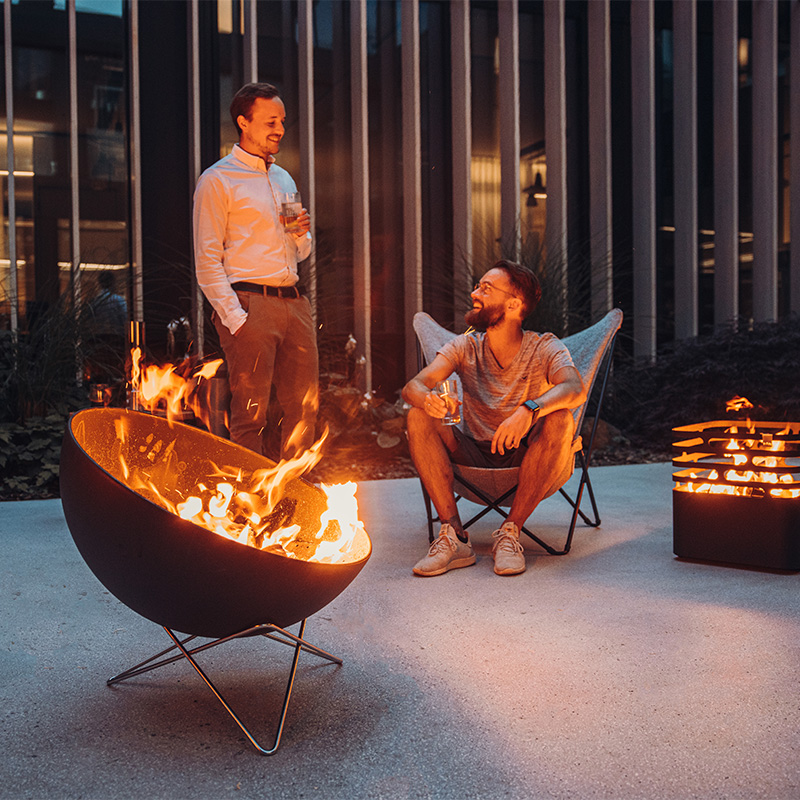 The Bowl Firebowl integrates seamlessly into the setting, where a man and woman sitting in chairs around a fire pit.