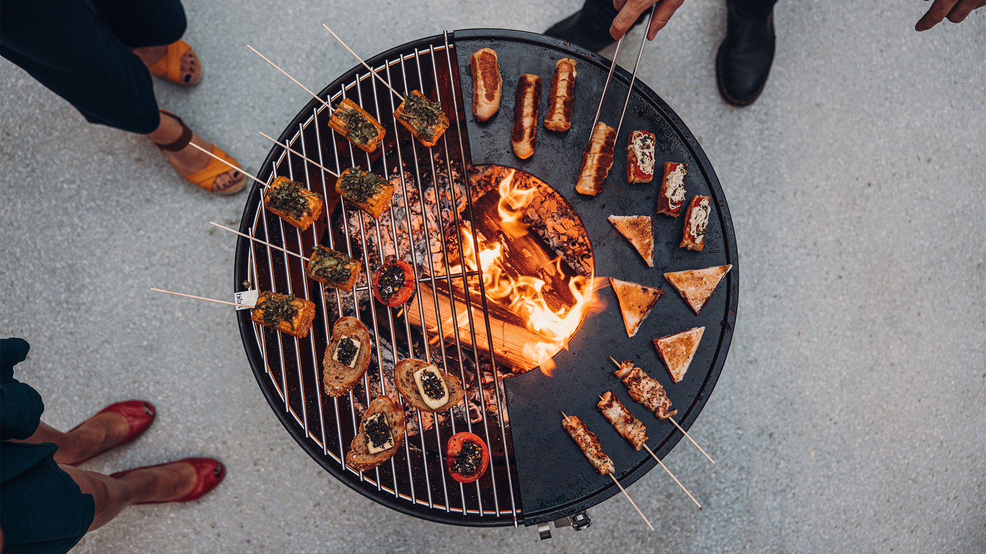 La photo présente un groupe de personnes debout autour d'un barbecue, avec la Grille BOWL 70.