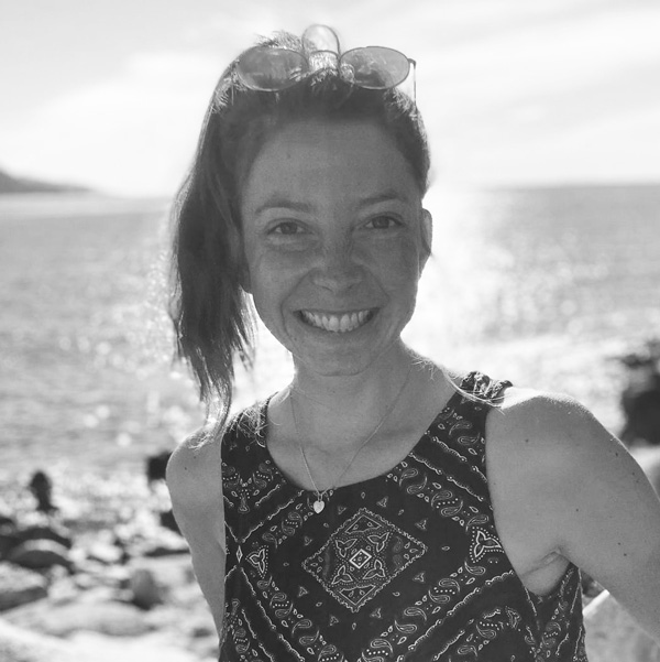 a woman standing on the beach with her arms crossed.