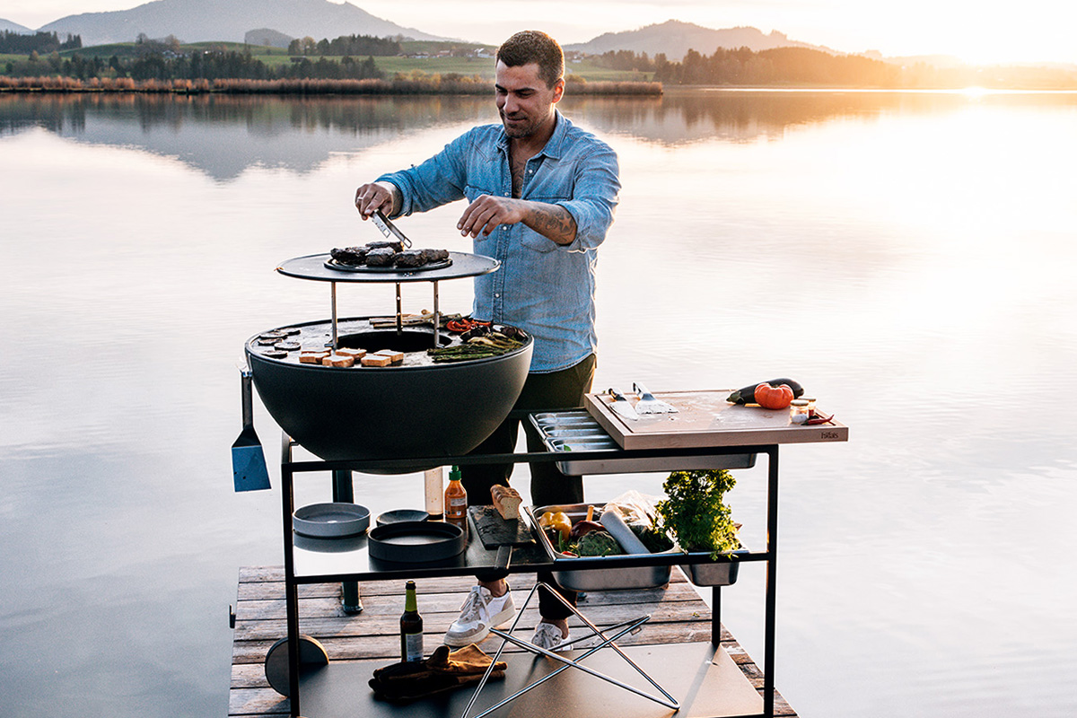 BOWL 70 Anneau Chauffant La photo montre un homme en train de cuisiner sur un grill, avec le BOWL 70 Warming Ring.