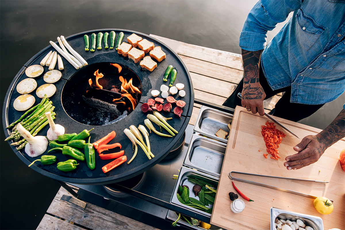 FIRE KITCHEN Stainless Steel Container Set (5 pcs) A man preparing food on a grill the 00764 FIRE KITCHEN Stainless Steel Container Set (5 pcs) complements the moment with its thoughtful design.