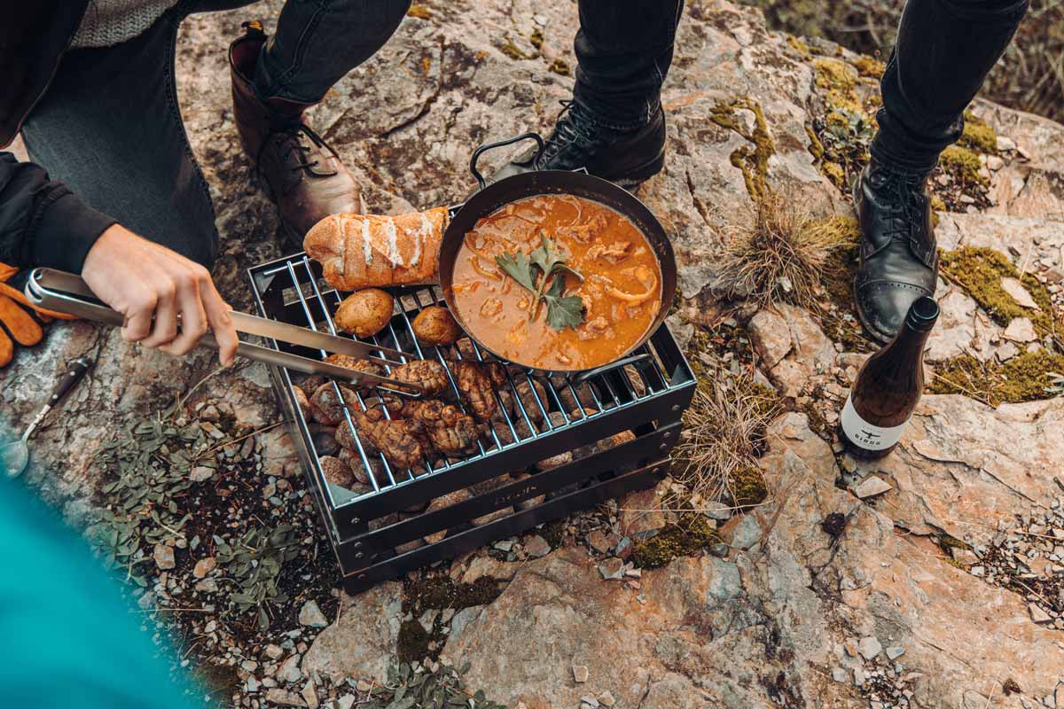 CRATE Grillrost Ein Bild zeigt einen Mann, der Essen auf einem Grill zubereitet, mit dem CRATE-Grillrost.