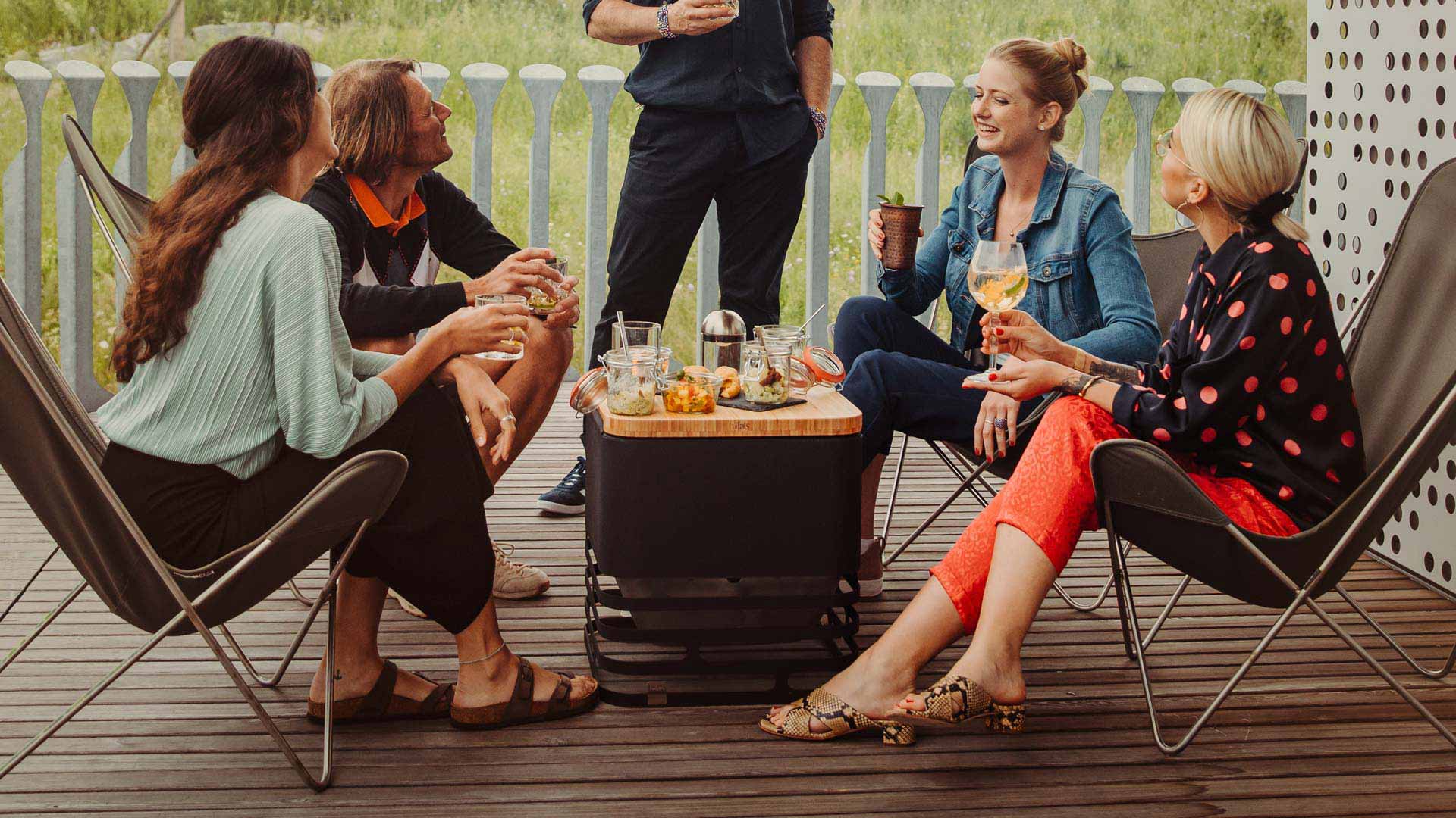 Hier ist eine Gruppe von Menschen abgebildet, die auf einer Terrasse sitzen und Wein trinken, mit dem CUBE Brett.