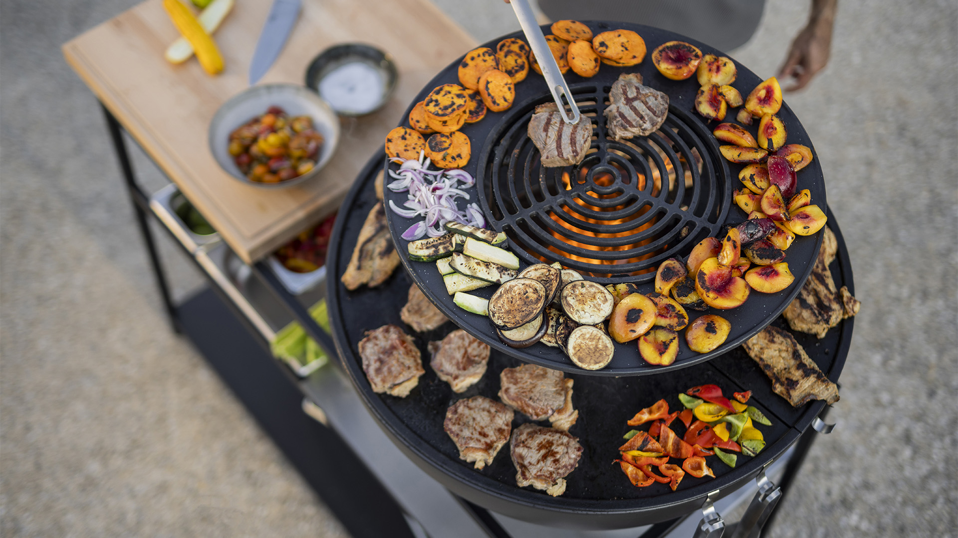 Scène montrant une personne en train de cuisiner une variété de plats, où le 00617 BOWL 70 Warming Ring se distingue par son élégance pratique.