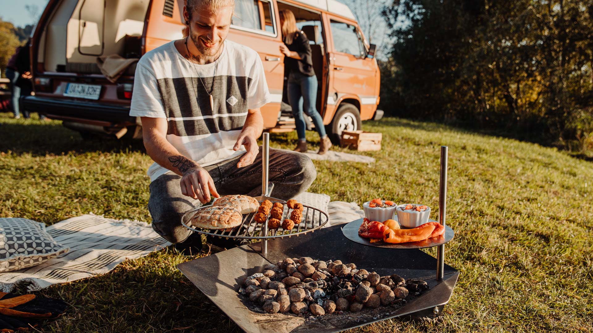 The Triple 90 Fireplace Multiset integrates seamlessly into the setting, where a man sitting on the grass with a grill.