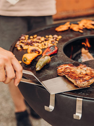 Ein Bild einer Person, die Essen auf einem Grill zubereitet, mit dem 00473 Spatula als zentralem und zweckmäßigem Element.
