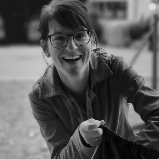 Une femme en lunettes sourit et tient un skateTablette.