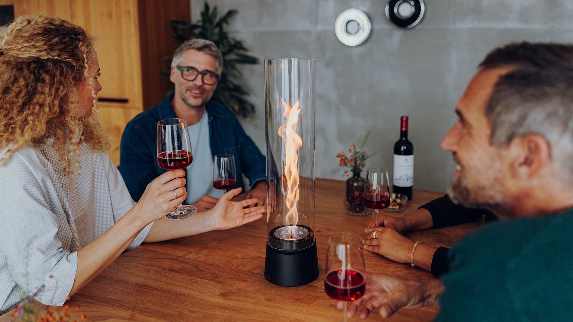 SPIN air 1200 und 900 mattschwarz auf einem Küchentisch mit vier Personen welche mit einem Rotwein anstoßen