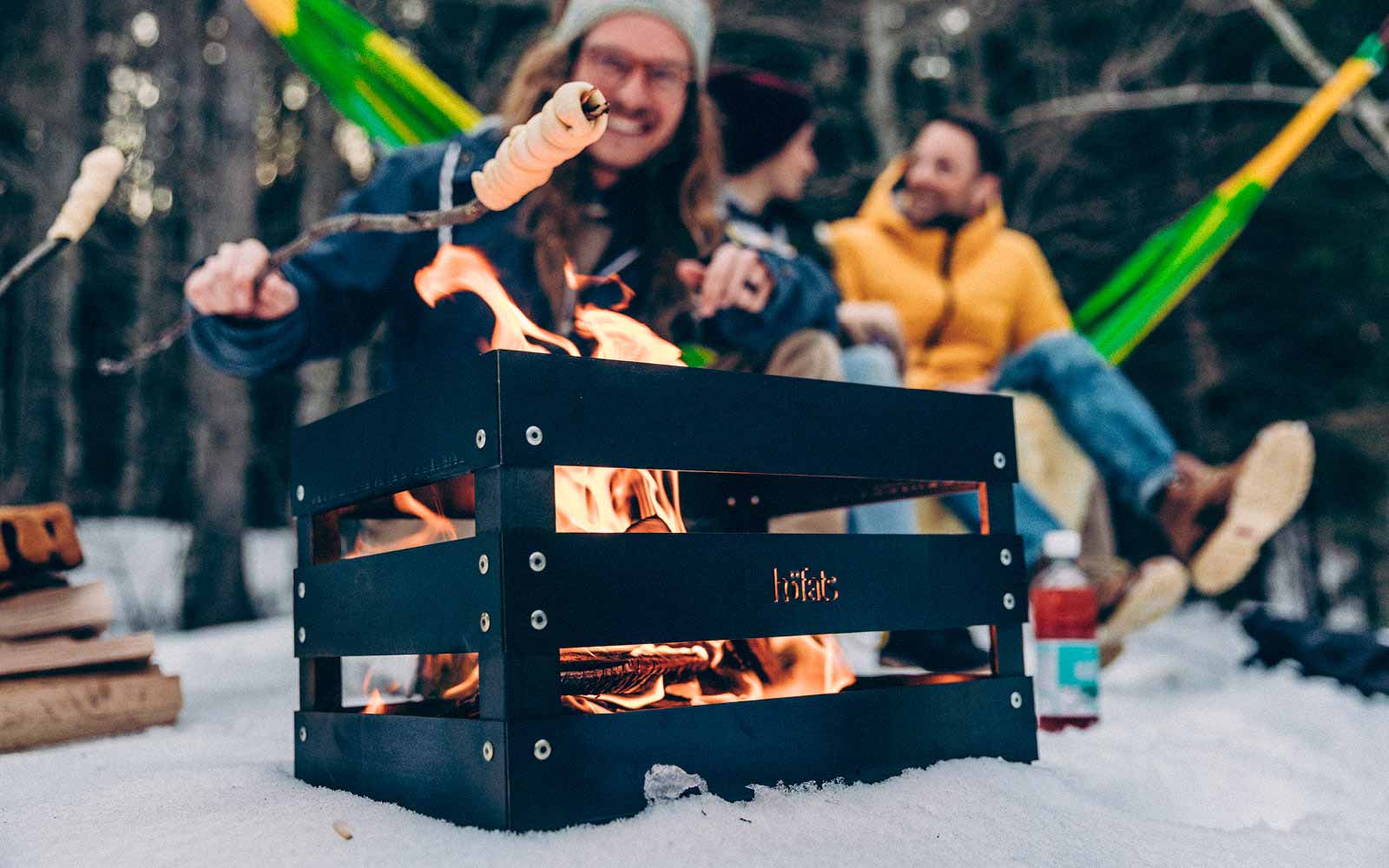 The photo presents a person is cooking something on a fire, with the SPIN 120 Table Fire silver.
