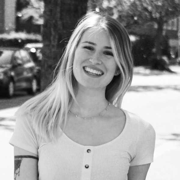 Une femme avec des tatouages debout devant un bâtiment.