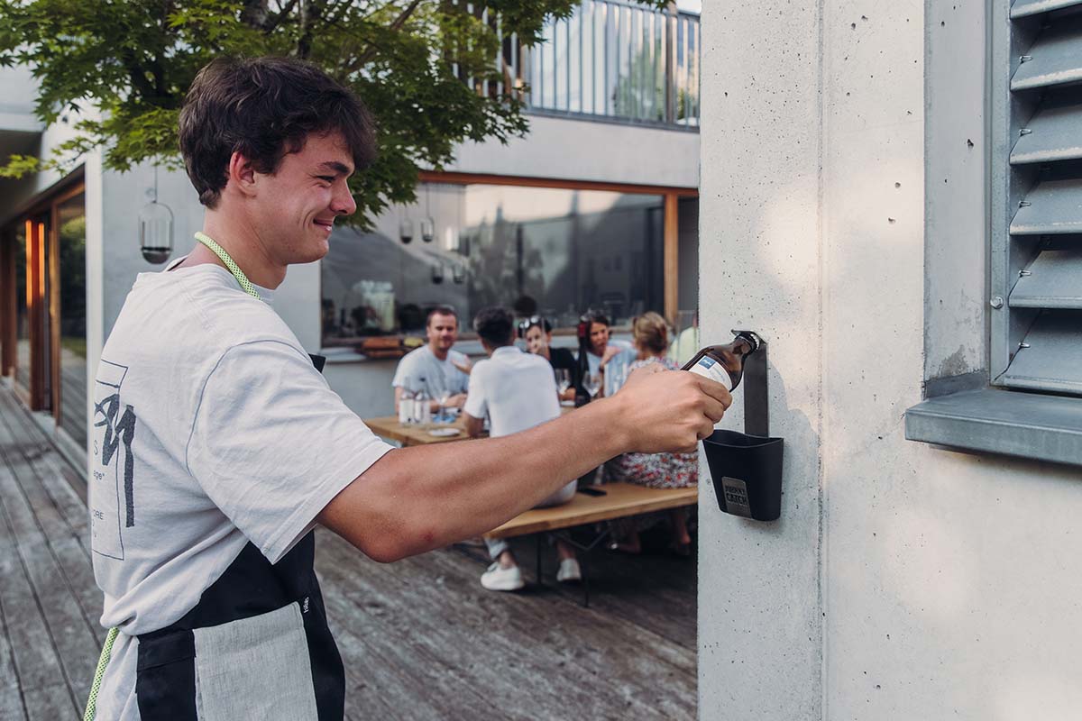 JOHNNY CATCH Gobelet Décapsuleur argent Une représentation d'un homme ouvrant une bouteille dans un restaurant, mettant en avant le Johnny Catch Cup ouvre-bouteille comme élément central et fonctionnel.