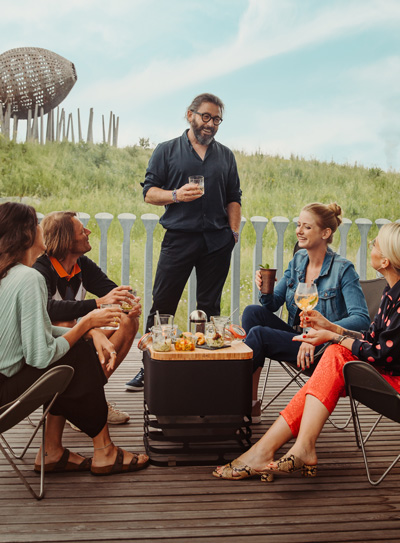 Depicted here is a group of people sitting around a fire pit, with the CUBE Fire basket black.