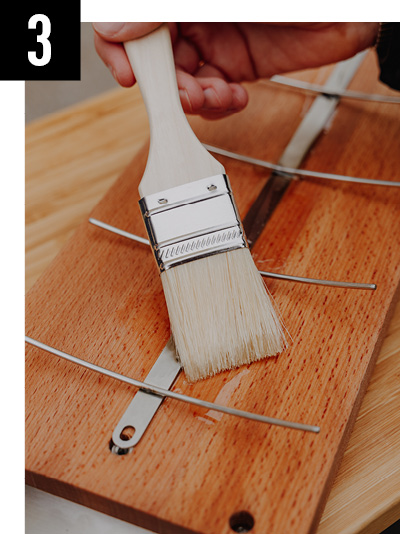 Une personne utilise un pinceau pour peindre un bloc de bois.