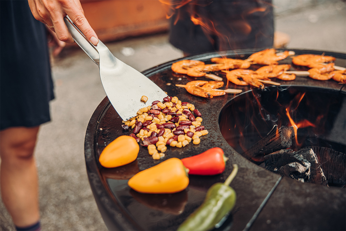 Hier ist eine Person beim Kochen von Essen auf einem Grill zu sehen.