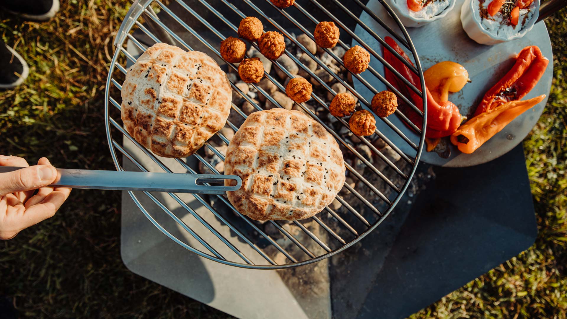 A person is cooking food on a grill the Triple Grid complements the moment with its thoughtful design.
