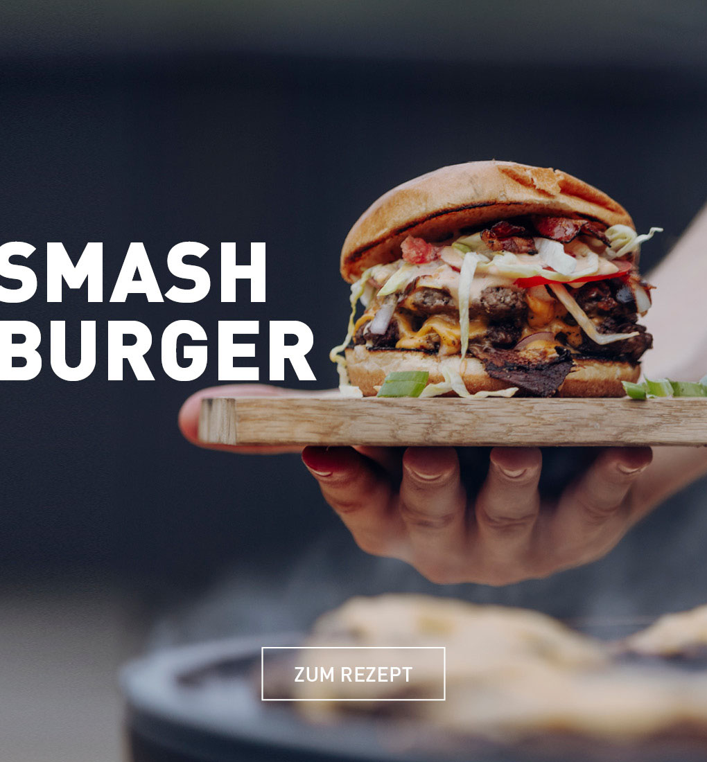 Eine Person hält einen Hamburger in der Hand.