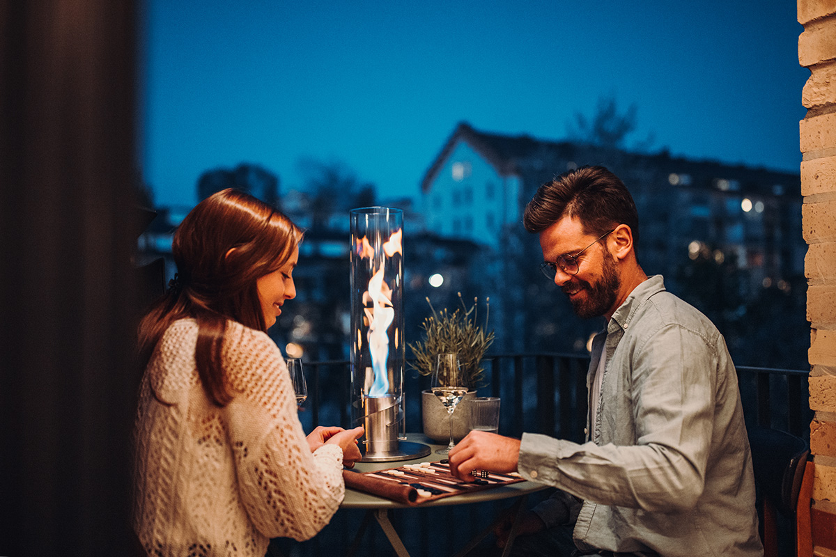 SPIN 120 Tischfeuer silber Die Spin 90 Tischfeuer in Silber fügt sich nahtlos in die Umgebung ein, wo ein Mann und eine Frau an einem Tisch mit einer Kerze sitzen.