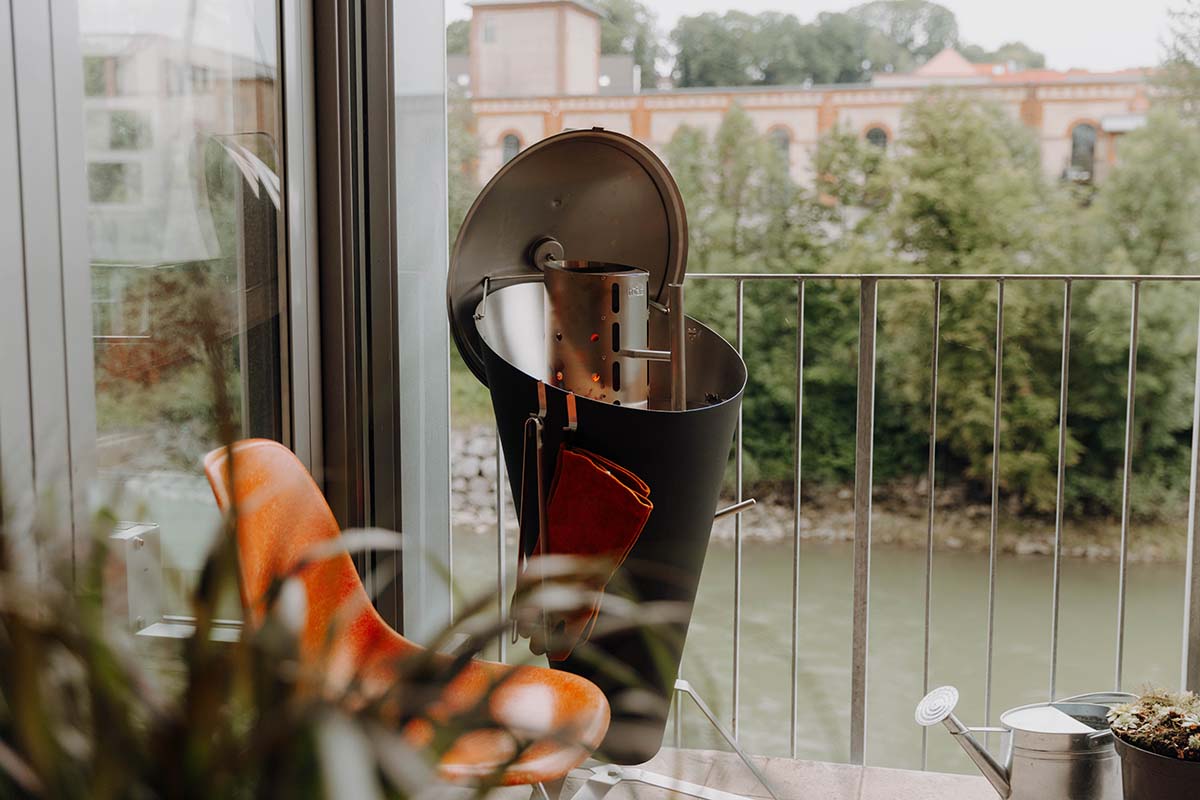 CONE Charcoal Grill Experience a pot of flowers on a table next to a window on a balcony. with the refined touch of the Cone Charcoal Grill