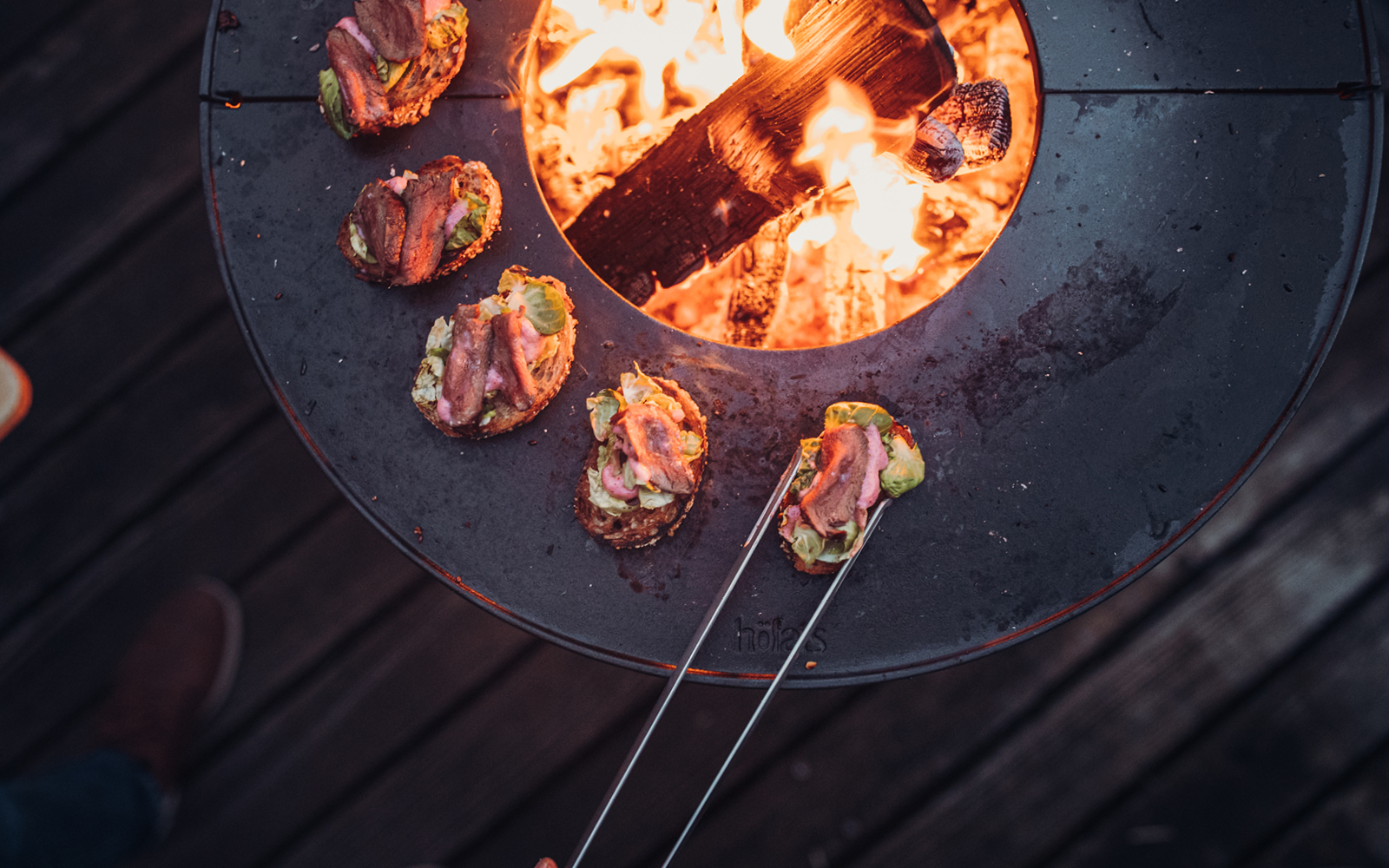 a person holding a spat over a fire