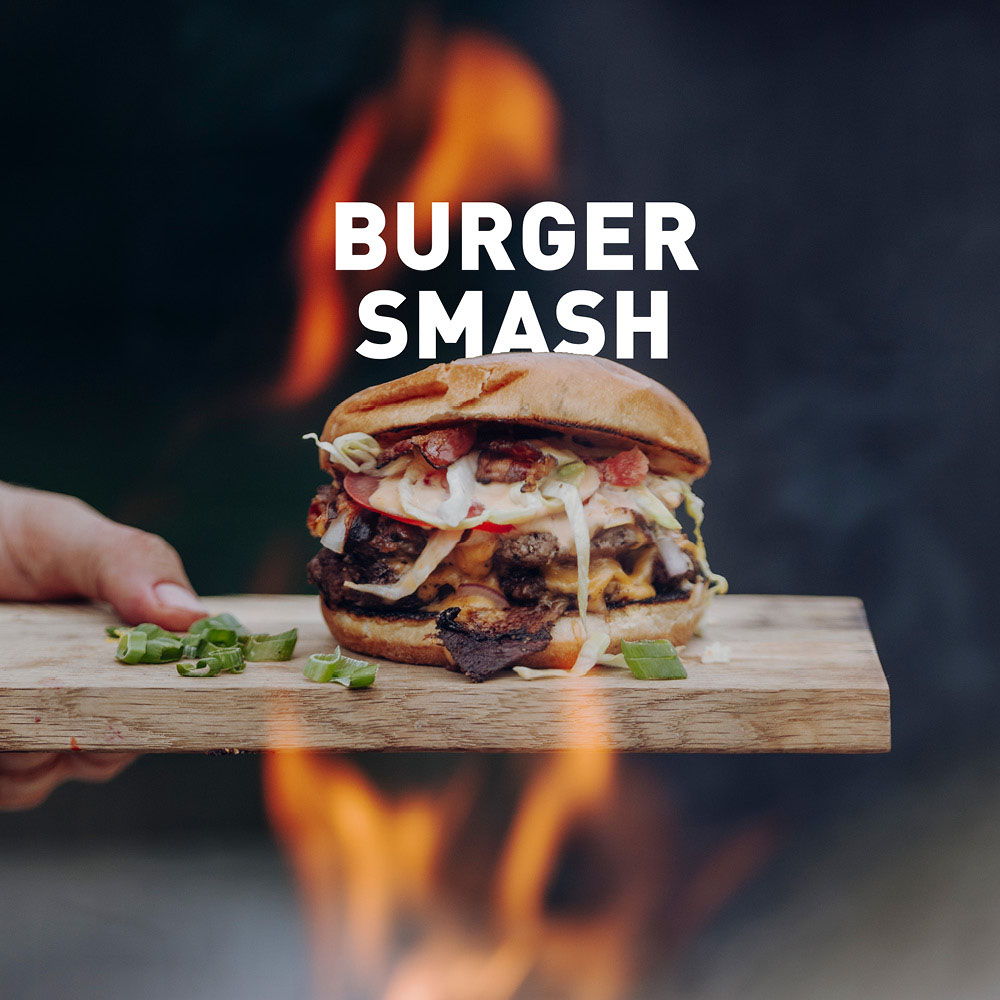 Une personne tenant un hamburger avec un feu en arrière-plan.