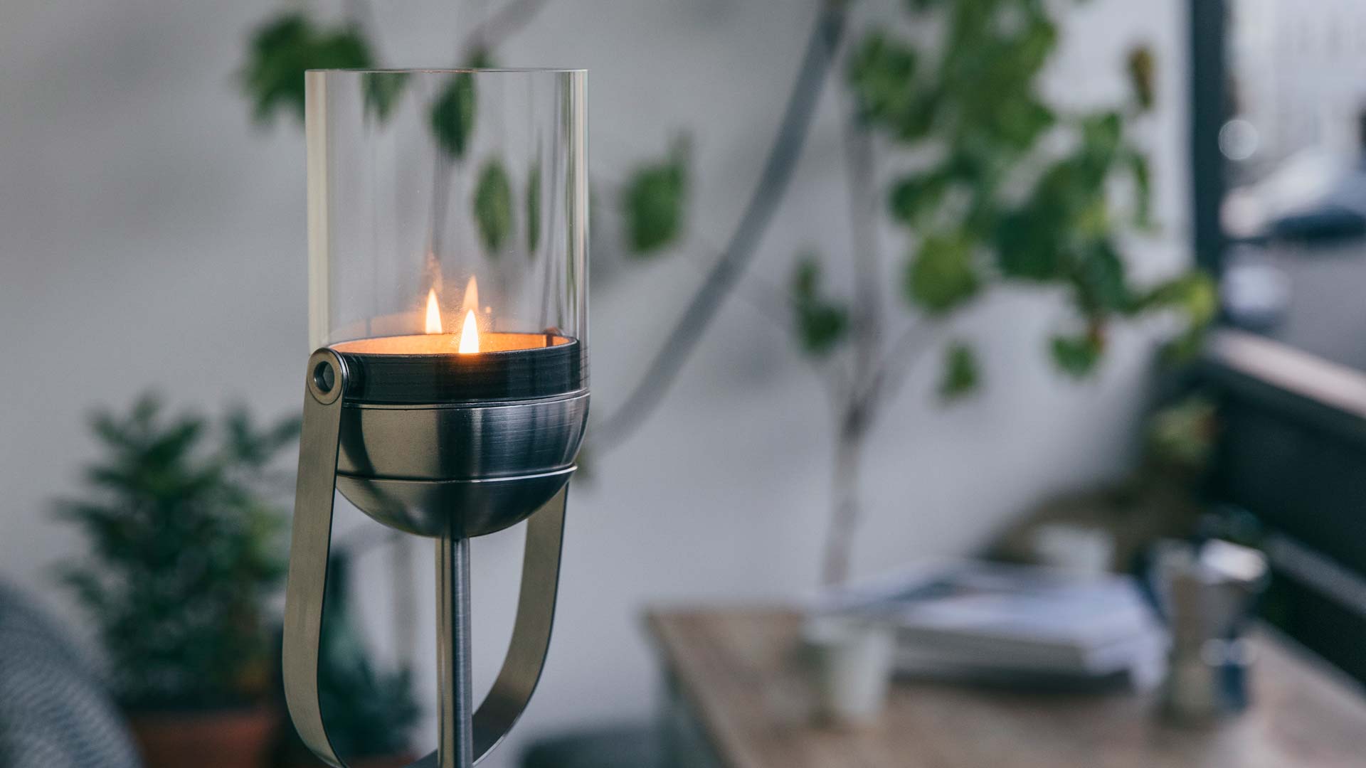 Une vue d'une bougie allumée dans un support en verre, avec la base GRAVITY CANDLE.