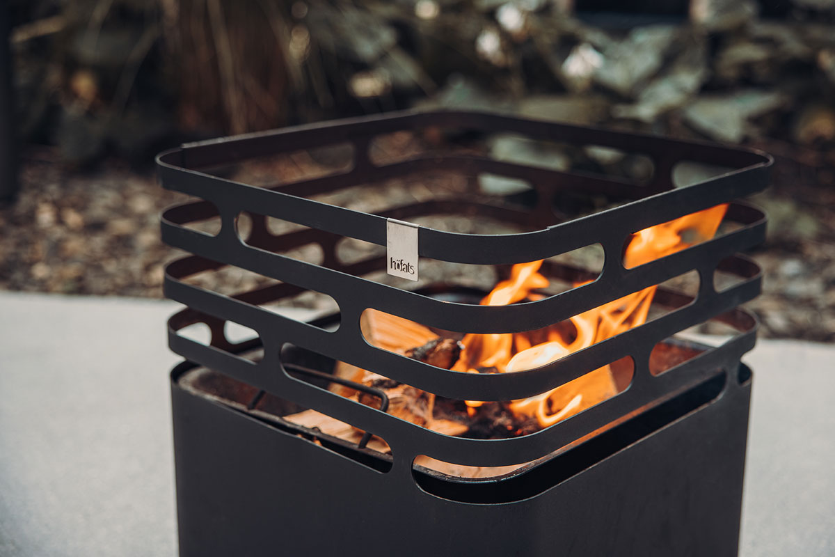 CUBE Fire Basket black The Cube Firebasket black integrates seamlessly into the setting, where a fire pit with a fire inside of it.