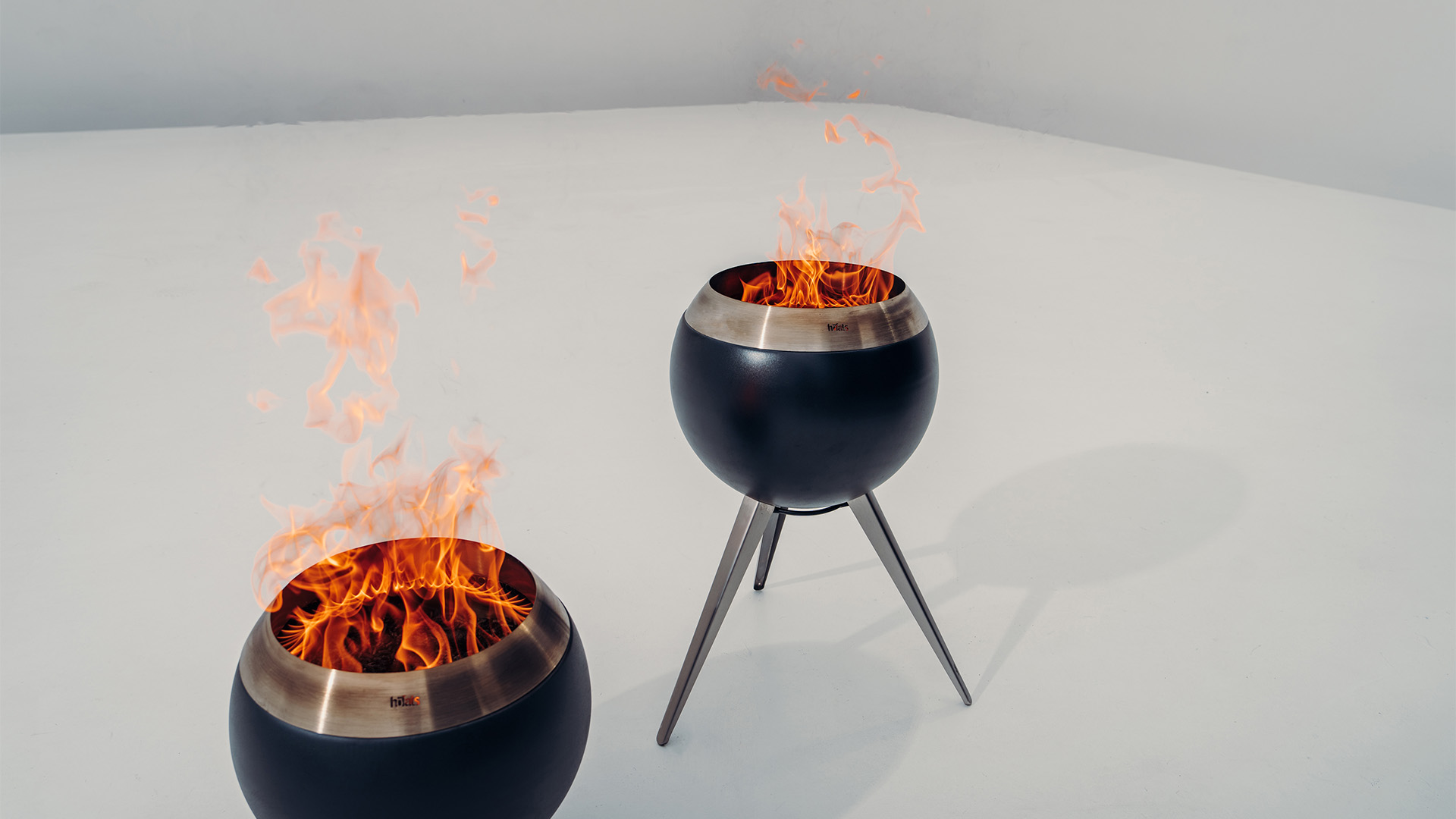 Two fire bowls on a white surface, with the 00717 Moon 45 with high stand adding a functional and elegant touch to the scene.