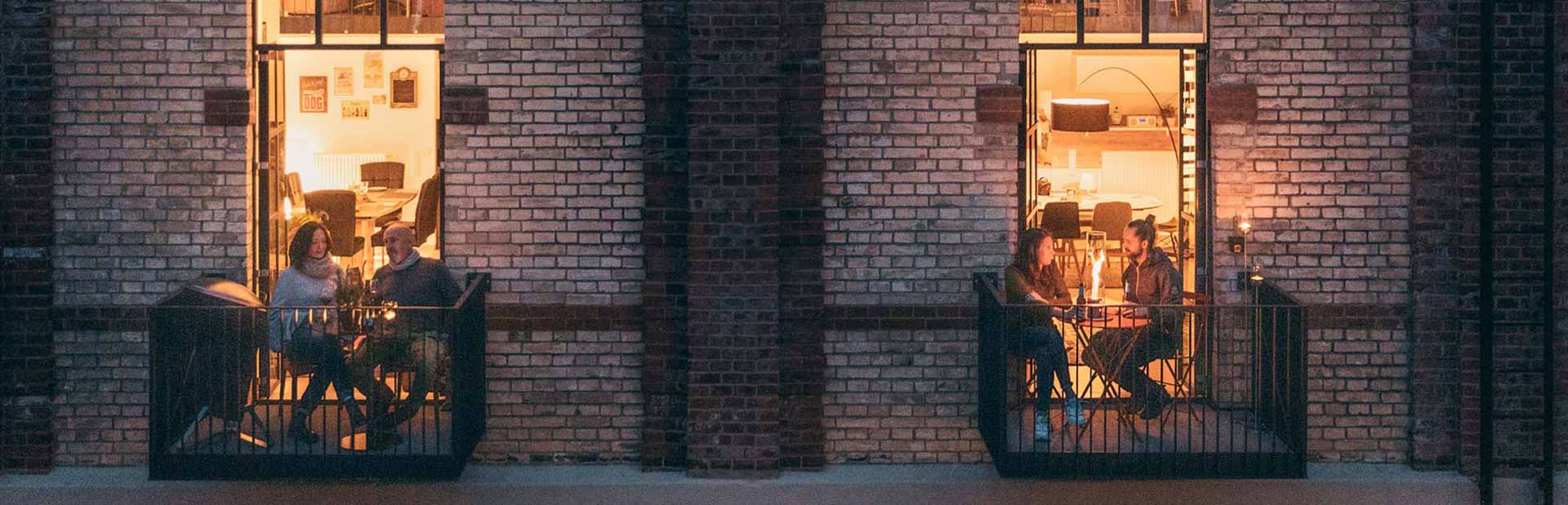 Auf dem Bild sind Menschen nachts auf dem Balkon eines Gebäudes zu sehen, mit dem CONE.