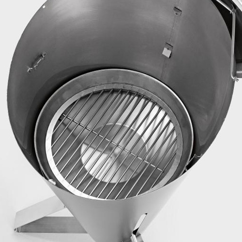 This image shows a large metal grill with a grilling basket on top, with the CONE Charcoal Grid.
