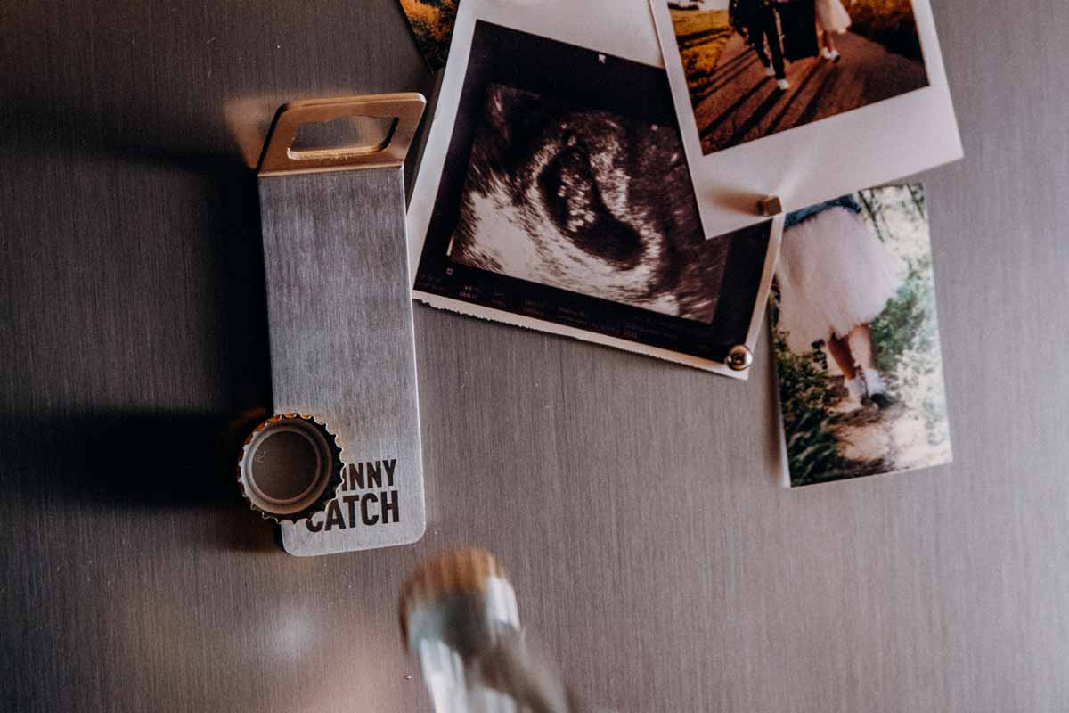 Cette image montre une table avec un tas de polaroids dessus, avec l'aimant JOHNNY CATCH.