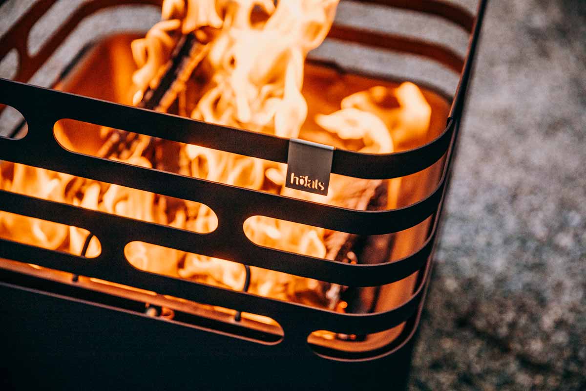 Ein Feuerkorb mit einem Metallgrill in der Mitte des Cube Firebasket in Schwarz ergänzt den Moment mit seinem durchdachten Design.