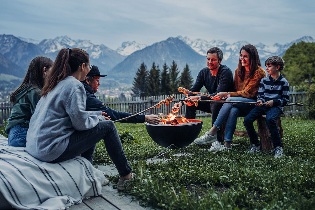 BOWL 57 Feuerset flex Auf dem Bild ist eine Gruppe von Personen abgebildet, die um eine Feuerstelle sitzen, mit dem BOWL 57 Fire Set flex.