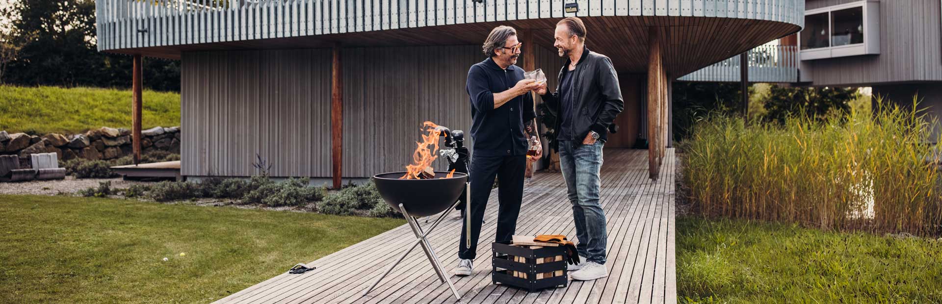 Deux hommes se tiennent sur une terrasse avec un barbecue, enrichie par la présence d'un bol qui allie design et utilité.