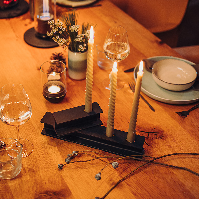 Illustrated is a wooden table, with the HENRY METAL II Candleholder black.