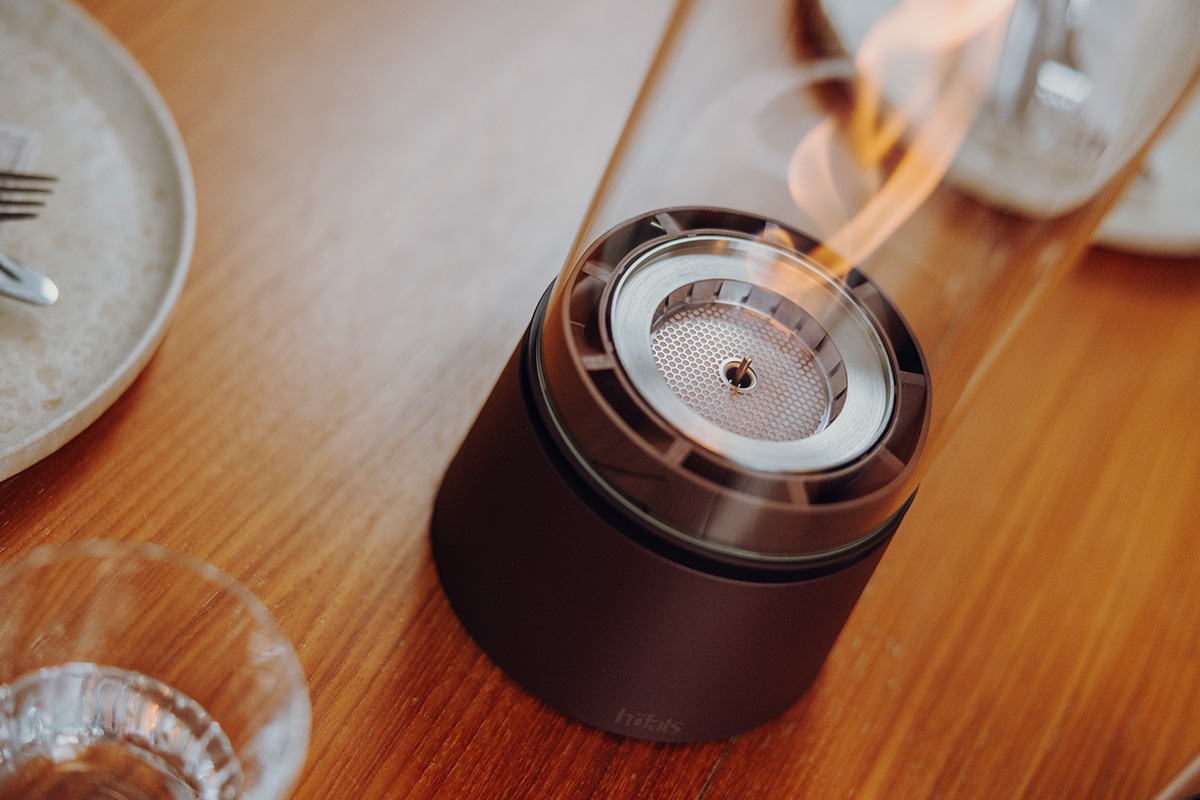 SPIN air 1200 rostbraun an einem runden Tisch mit Tellern und Menschen Close-Up