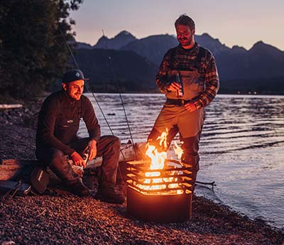 Zwei Männer sitzen um ein Lagerfeuer herum.