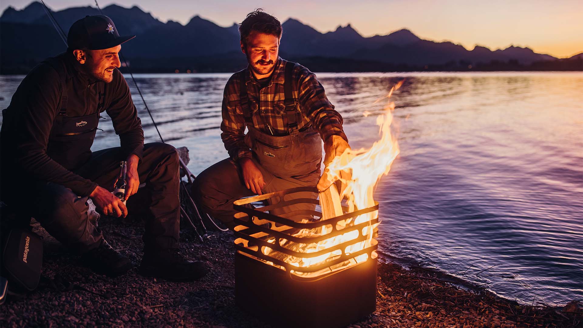 Deux hommes assis autour d'un feu de camp, le CUBE brasero rouillé complète le moment avec son design réfléchi.