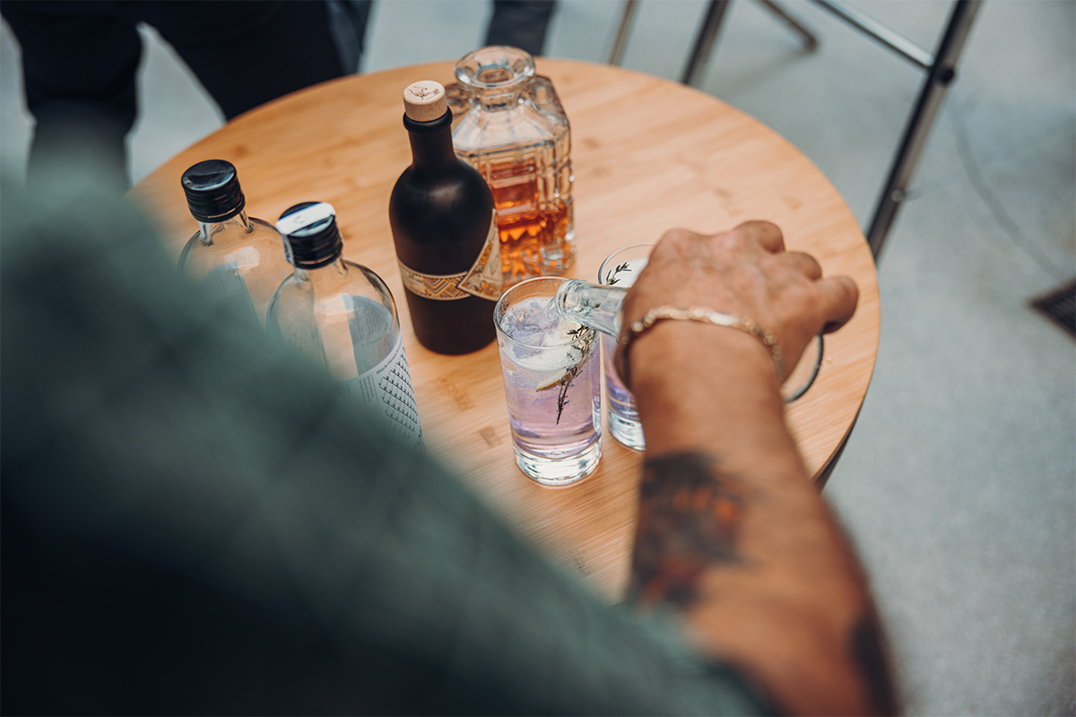 BOWL 57 Auflagebrett Auf dem Bild ist eine Person dargestellt, die an einem Tisch mit einer Flasche Alkohol sitzt, mit dem BOWL 57 Brett.