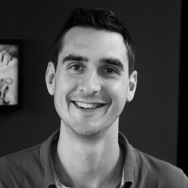 Un homme souriant sur une photo en noir et blanc.