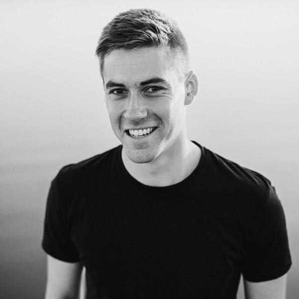 Un homme souriant debout devant un lac.