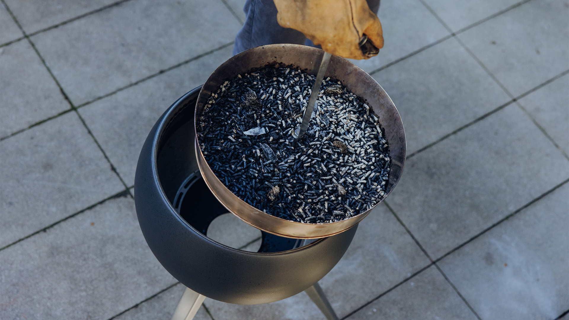 Le 00832 MOON 45 Elevation pour cendrier est représenté par une personne tenant un bol de granulés de bois brûlés, créant une image élégante et accessible.