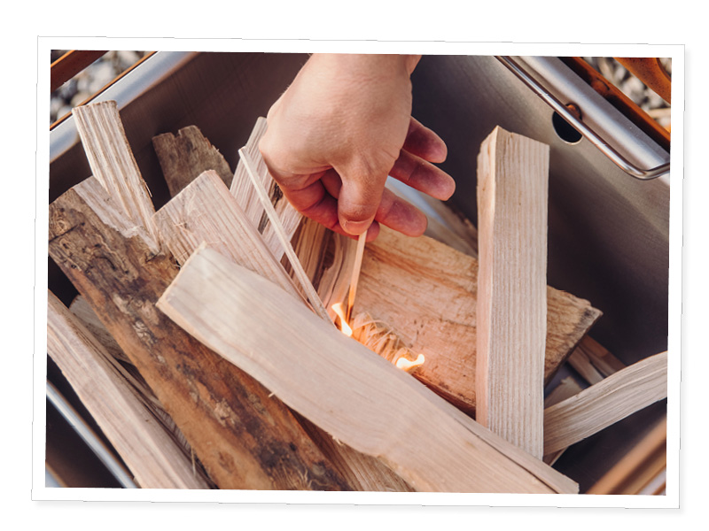 Une personne met du bois dans un feu