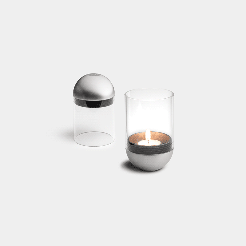 Abgebildet ist eine Kerze und ein Glasbehälter auf einer weißen Oberfläche, mit der GRAVITY CANDLE M90 Laterne.