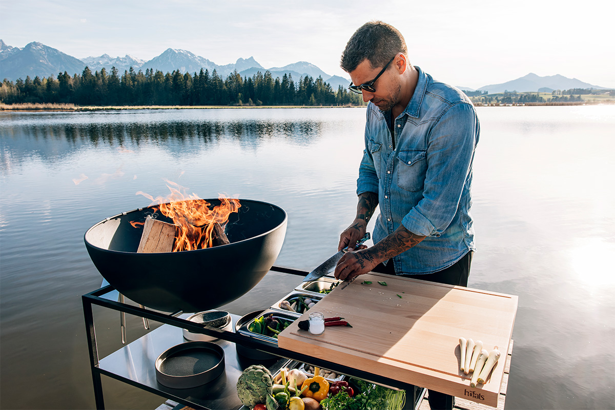 Un homme cuisine sur un grill, avec le plan de travail de cuisine 00614 Fire ajoutant une touche fonctionnelle et élégante à la scène.