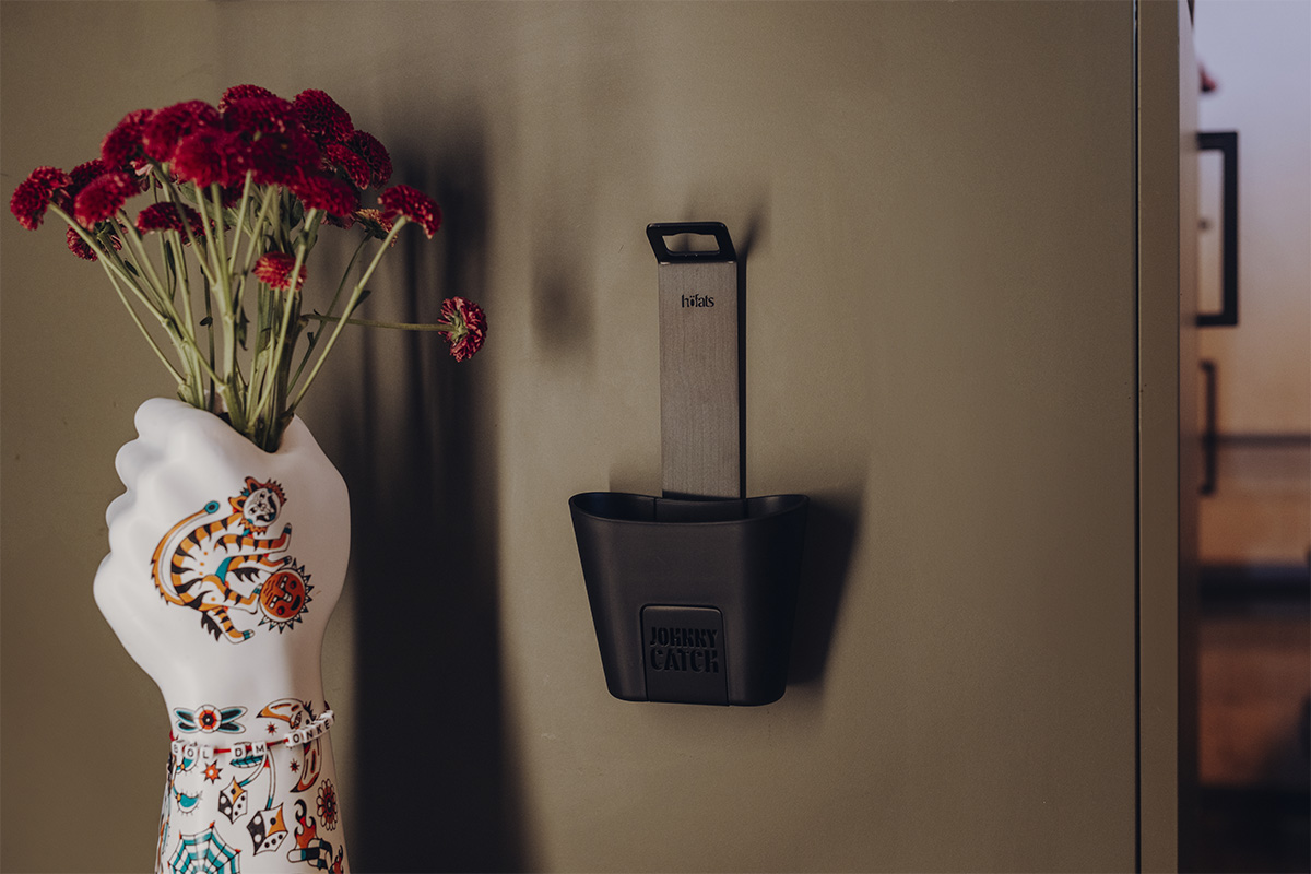 Der 00842 Johnny Catch Cup Black Flaschenöffner fügt sich nahtlos in die Umgebung ein und zeigt eine Vase in Form einer Hand mit Blumen.